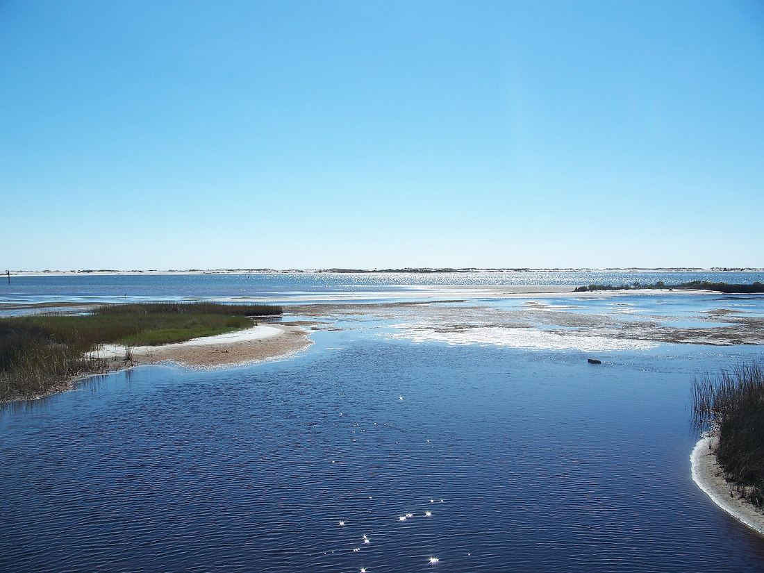 Clear shallow water and a sand bar at Big Lagoon State Park with barrier island dunes across the lagoon