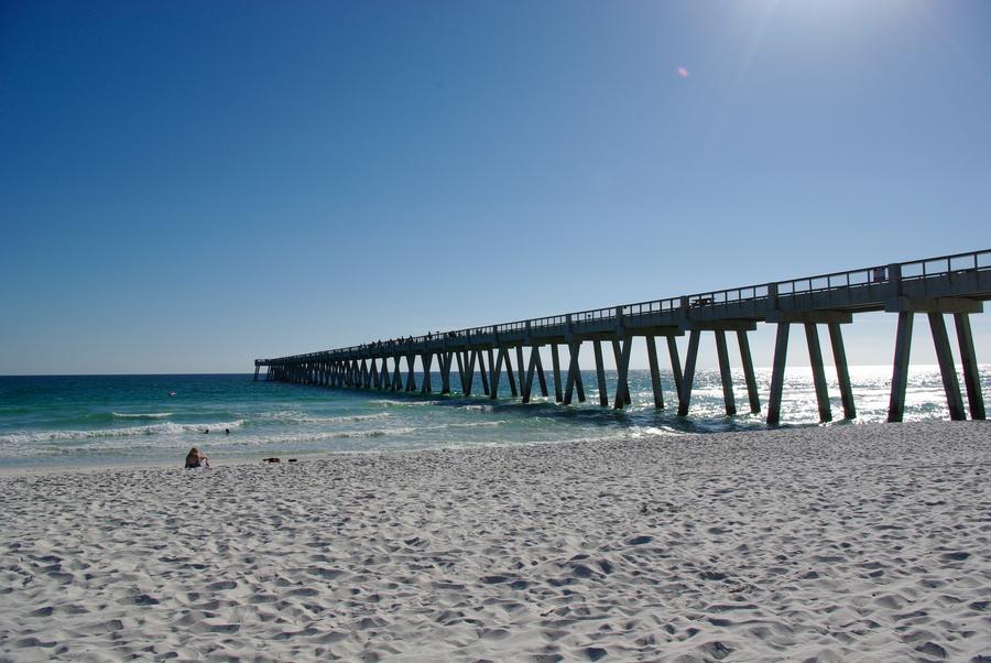 Long concrete fishing pier extending into the Gulf from the sand at Navarre Beach, Florida