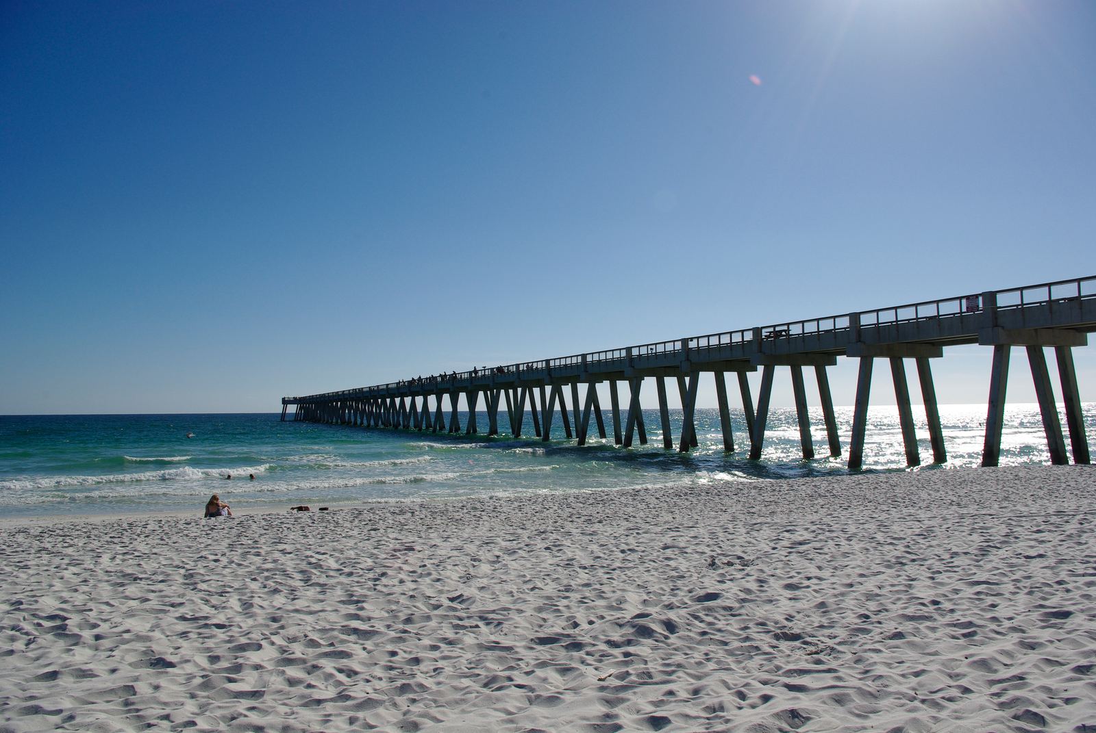 Long concrete fishing pier extending into the Gulf from the sand at Navarre Beach, Florida